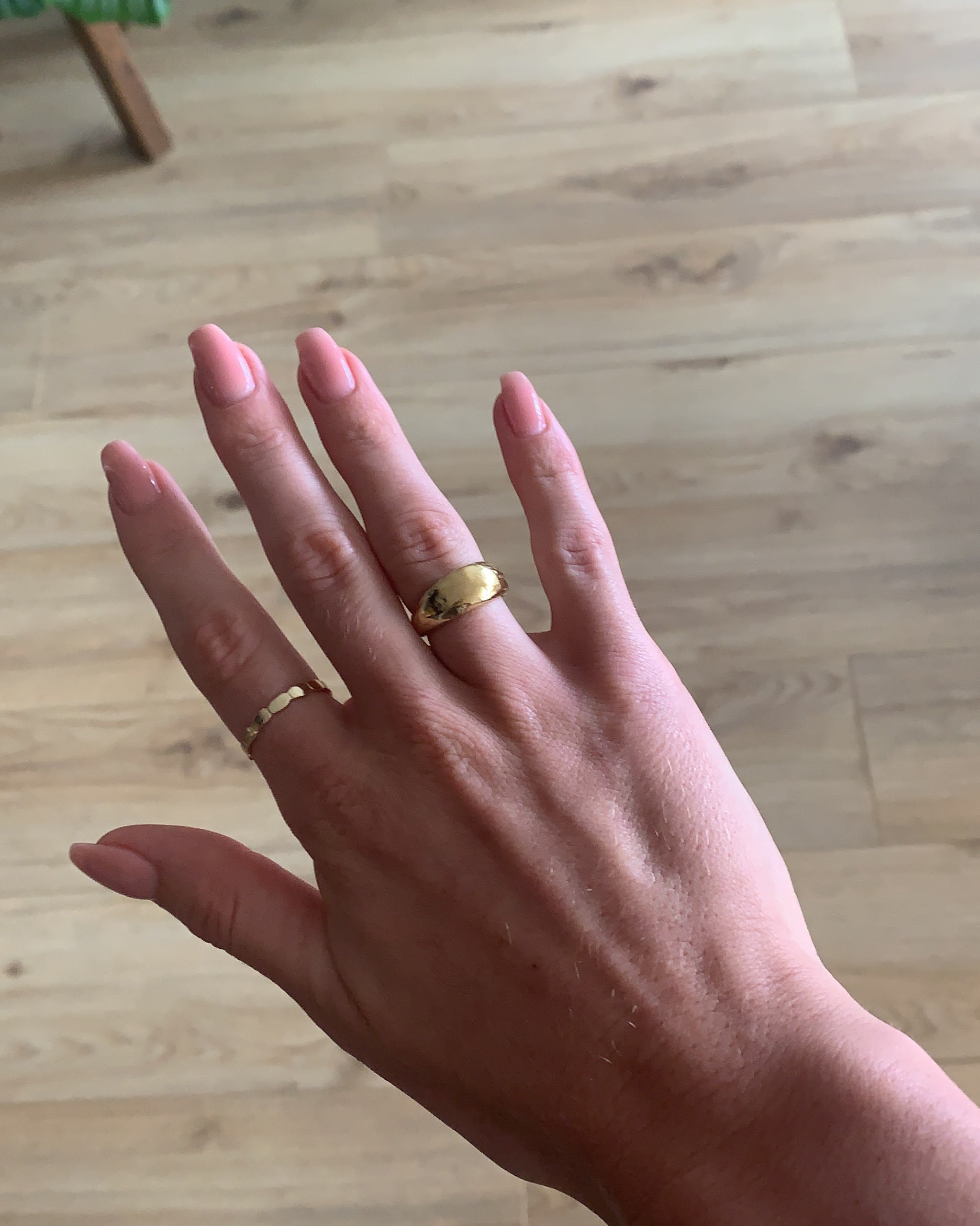 Hand met ringen en nude-roze nagels
